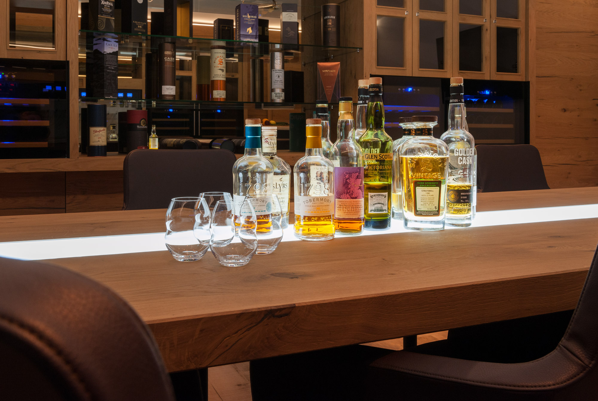 Mehrere Single Malt Wiskeys auf einem Holztisch.